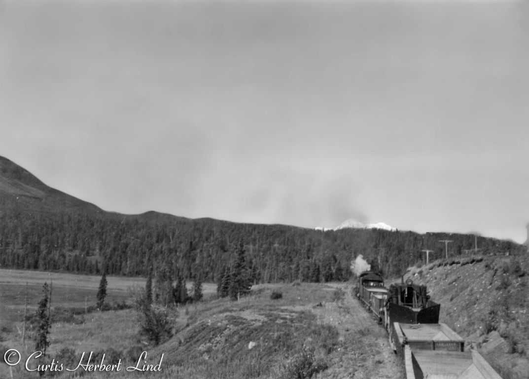 Climbing the hill from Chulitna up to Hurricane, the mountain is Denali, MP 273 to MP 277. MOW crews with empty Hart Convertible Gons and a Jordan spreader tow headed back to the pit. These were wood gondolas with floor decks that could be configured to dump between the rails or outside the rails. These are empty and appear to be configured to dump between the rails where the Jordan spreader could then plow it out to the final grade.